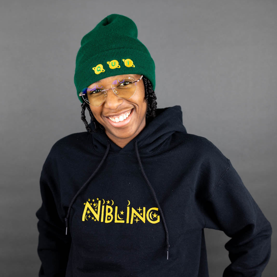 Kassidy wearing a spruce green 'qui' beanie