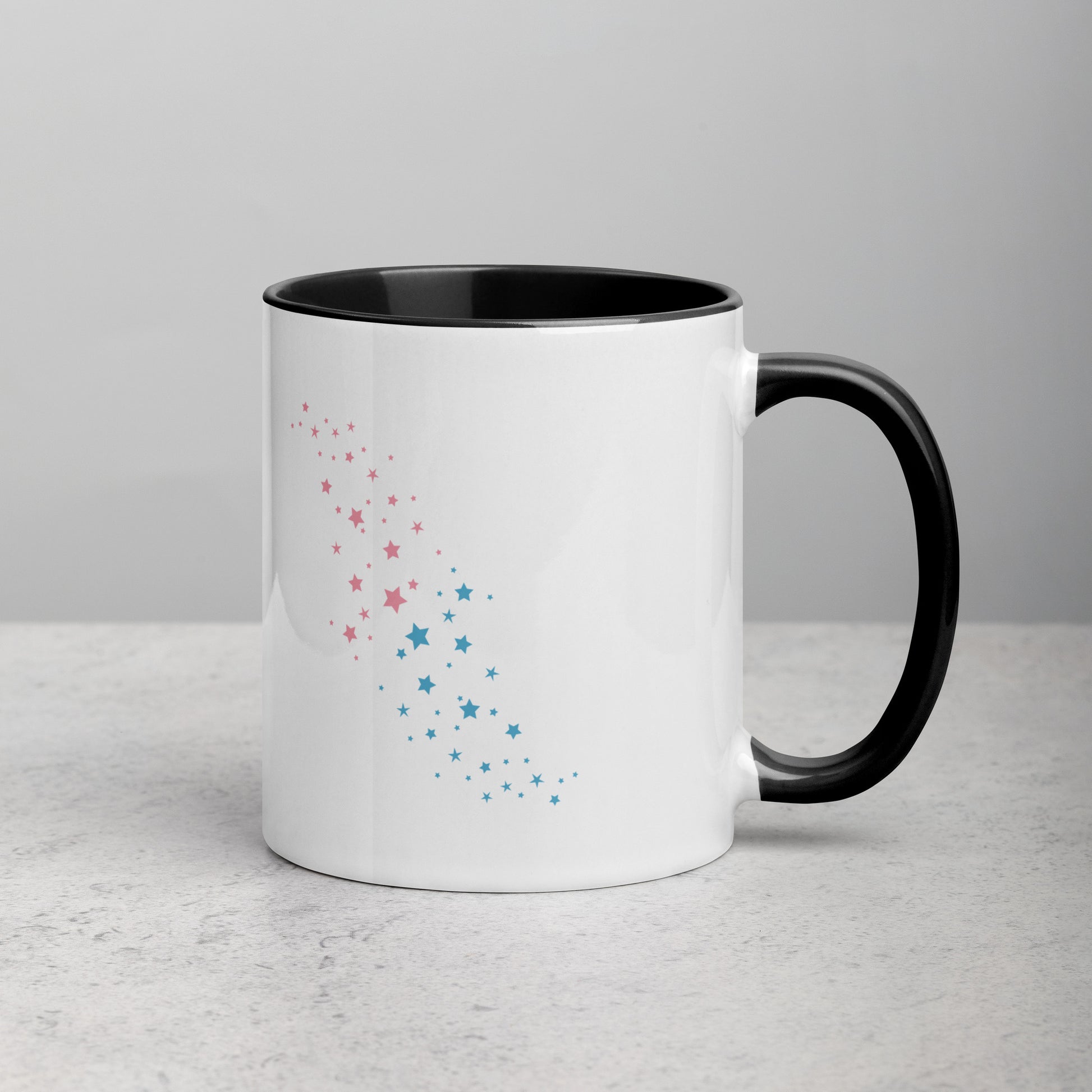 Back view of white ceramic mug with black handle and interior, featuring a celestial pattern of pink and blue stars arranged diagonally; designed by Galactic Flow for cosmic self-expression
