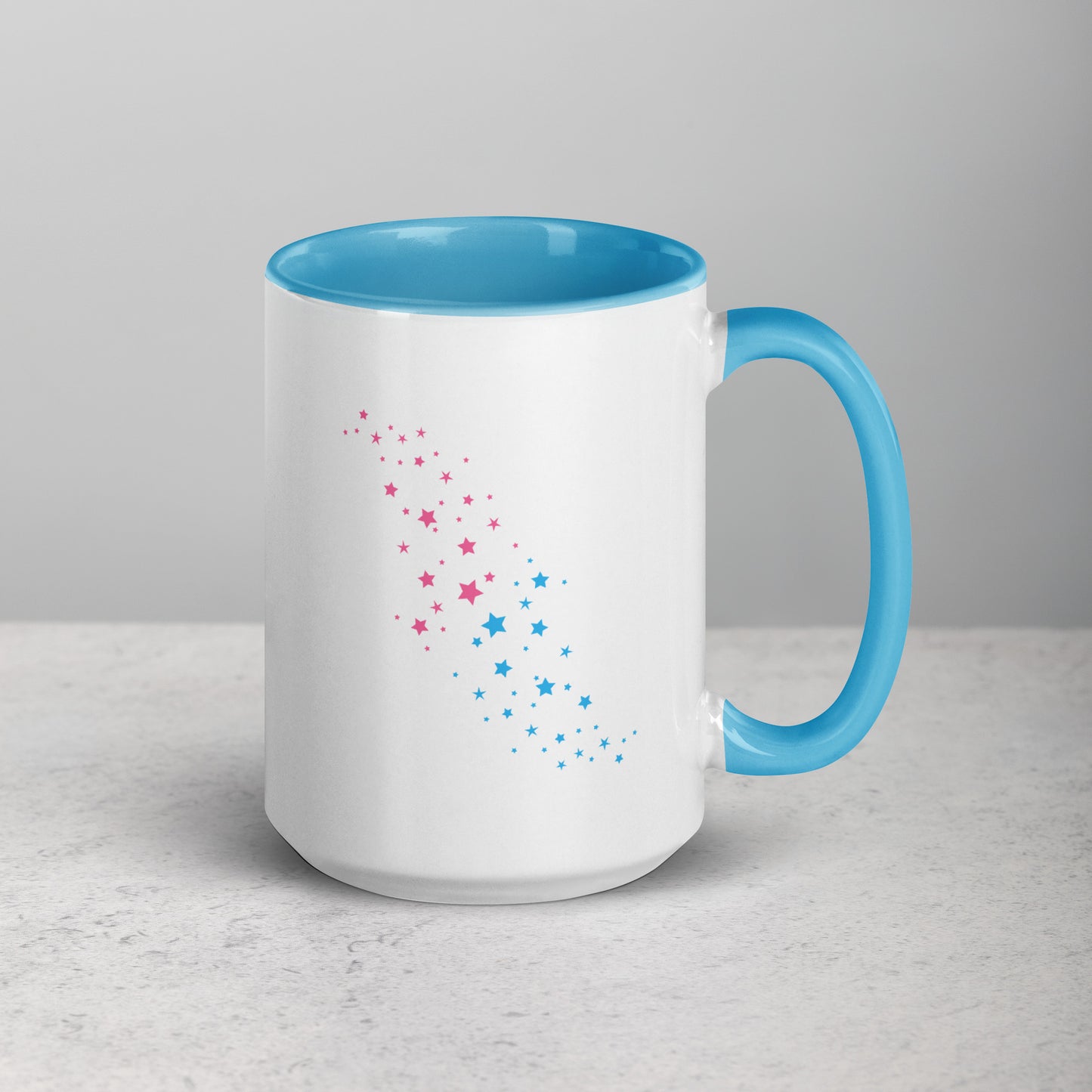 White mug with blue interior and handle, featuring pink and blue star patterns on a light gray background.