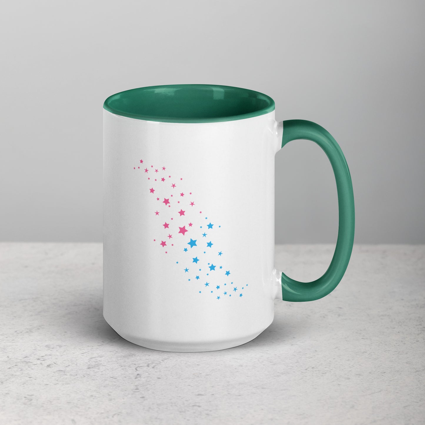 White mug with dark green interior and handle, featuring pink and blue star patterns on a light gray background.