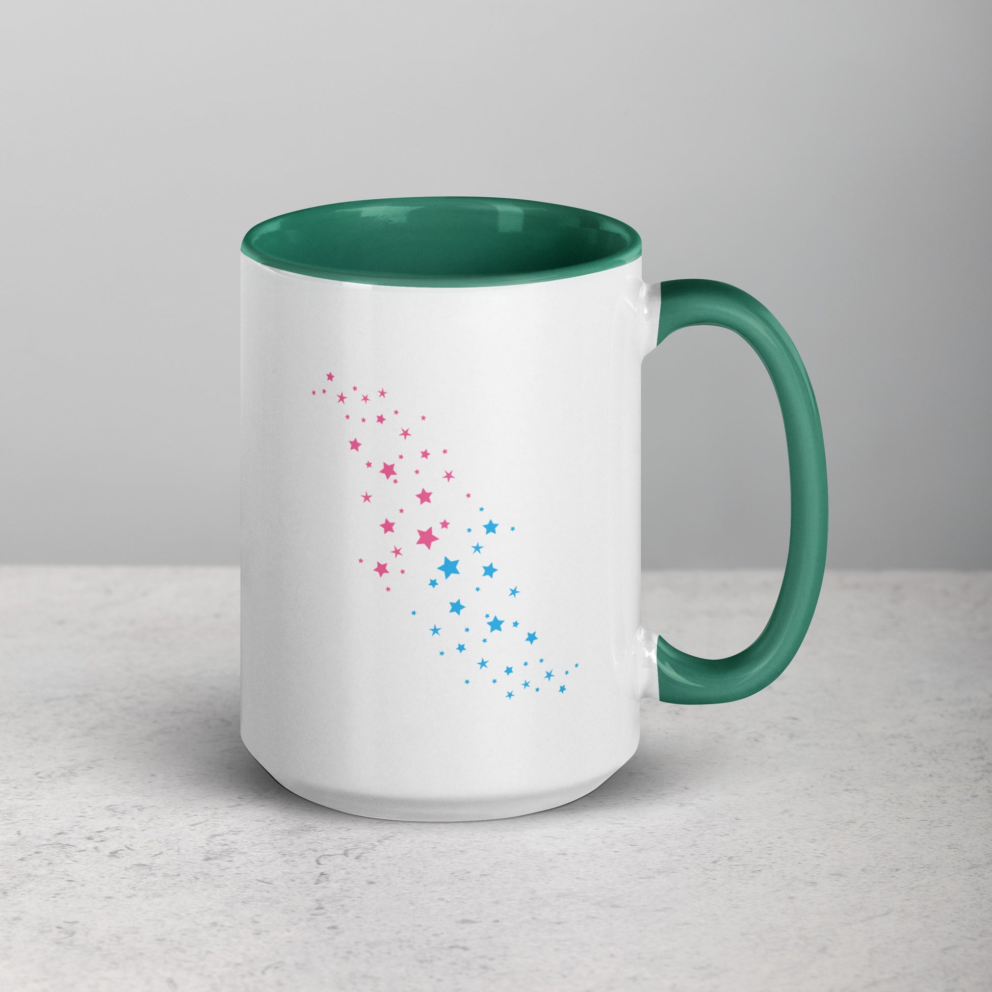 White mug with dark green interior and handle, featuring pink and blue star patterns on a light gray background.